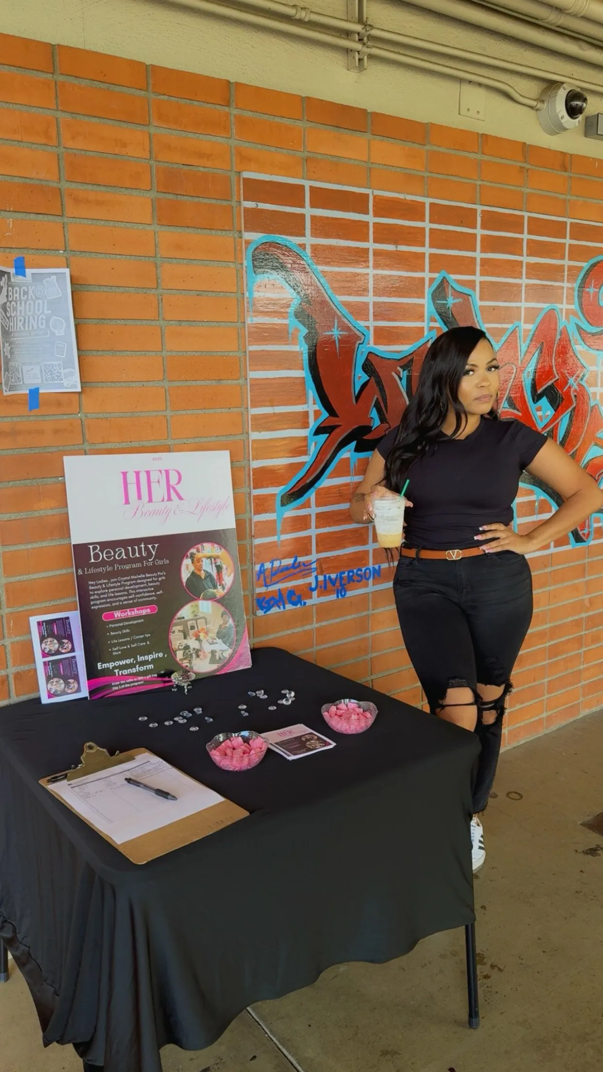Crystal Michelle beside the H.E.R Beauty and Lifestyle sign-up table at a school