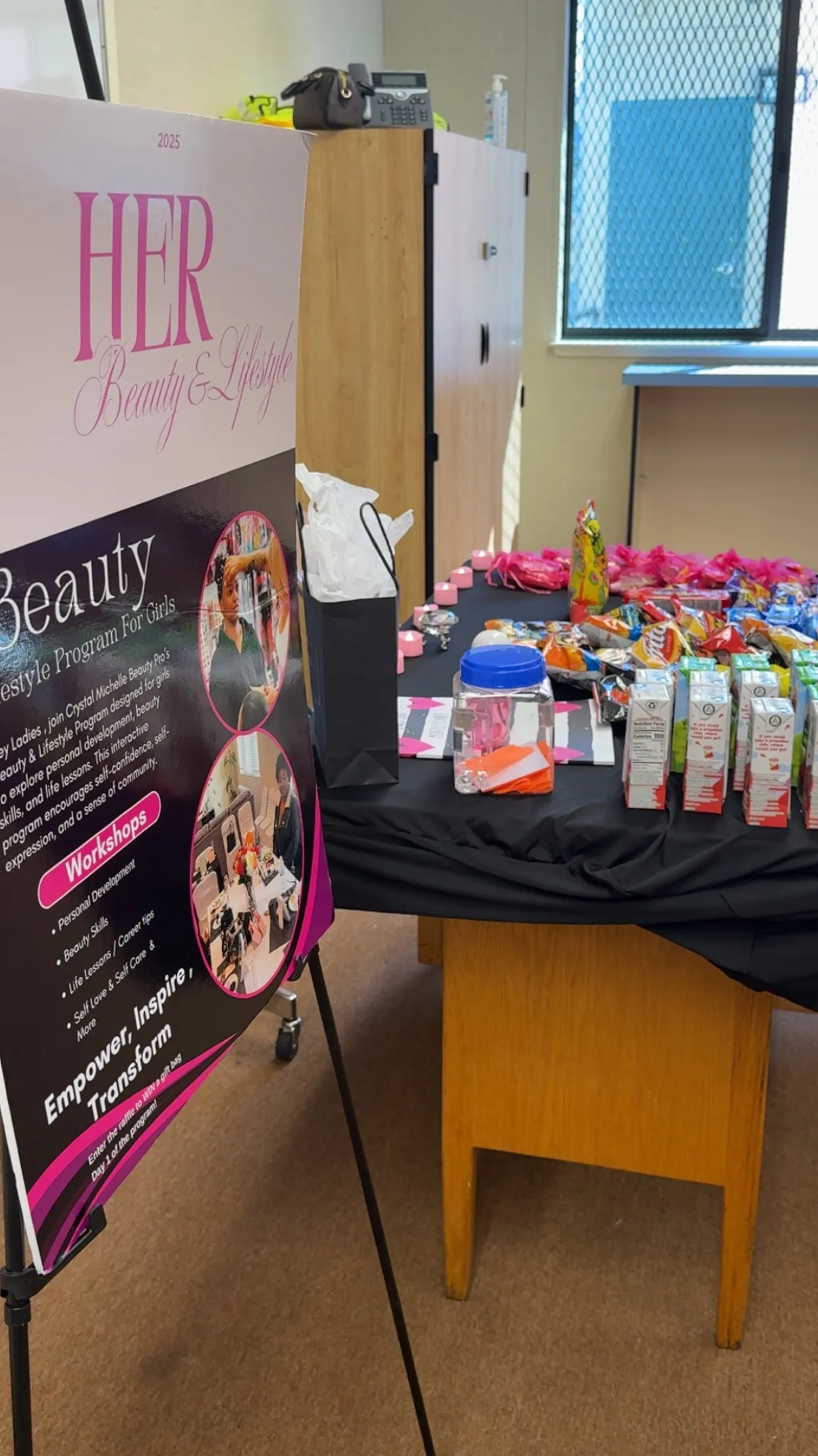 The H.E.R programme banner next to a table of gift bags and snacks