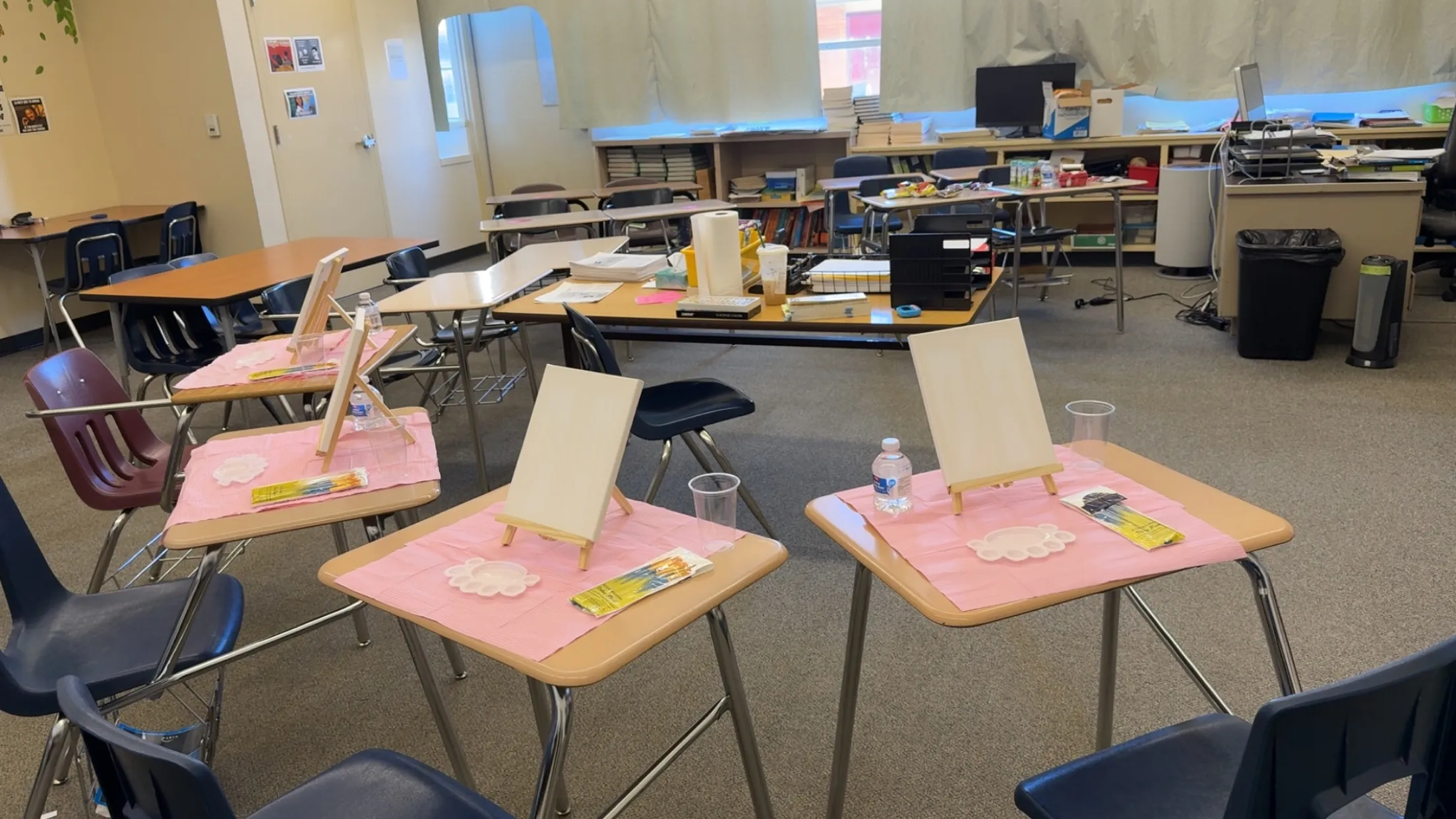 A classroom set up for a paint workshop, blank canvases on every desk