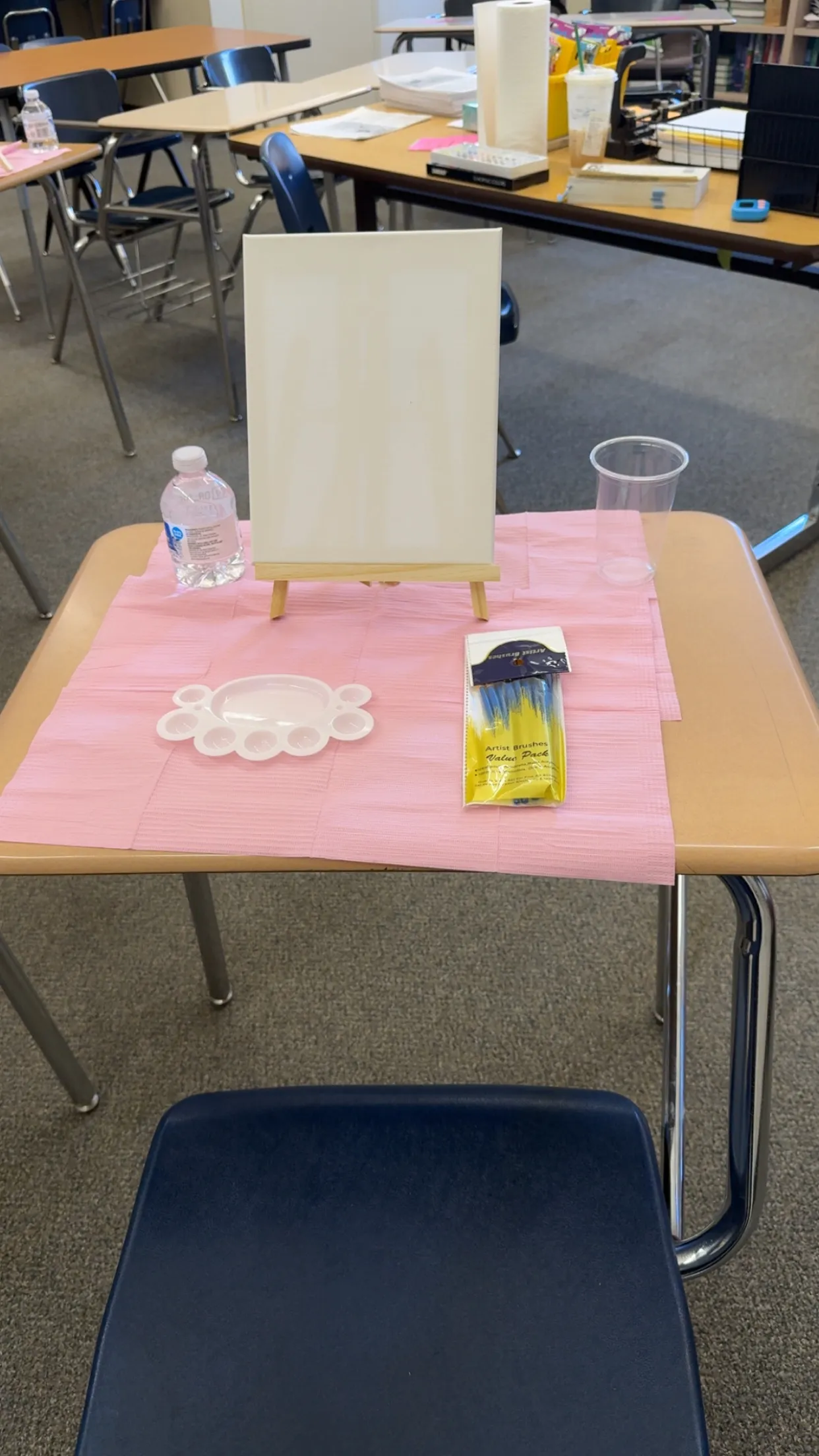 One desk set for painting: canvas on an easel, palette, brushes and water