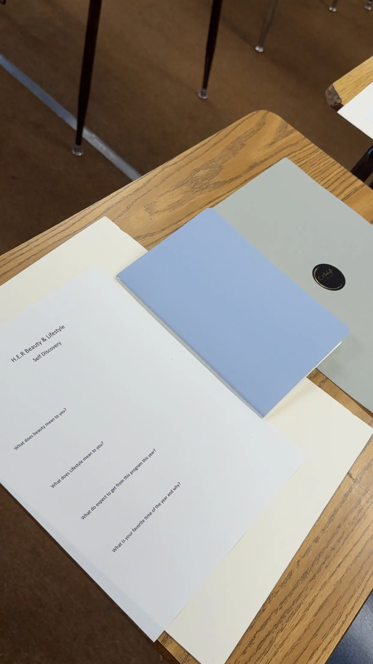 The H.E.R Self Discovery worksheet beside a journal on a desk