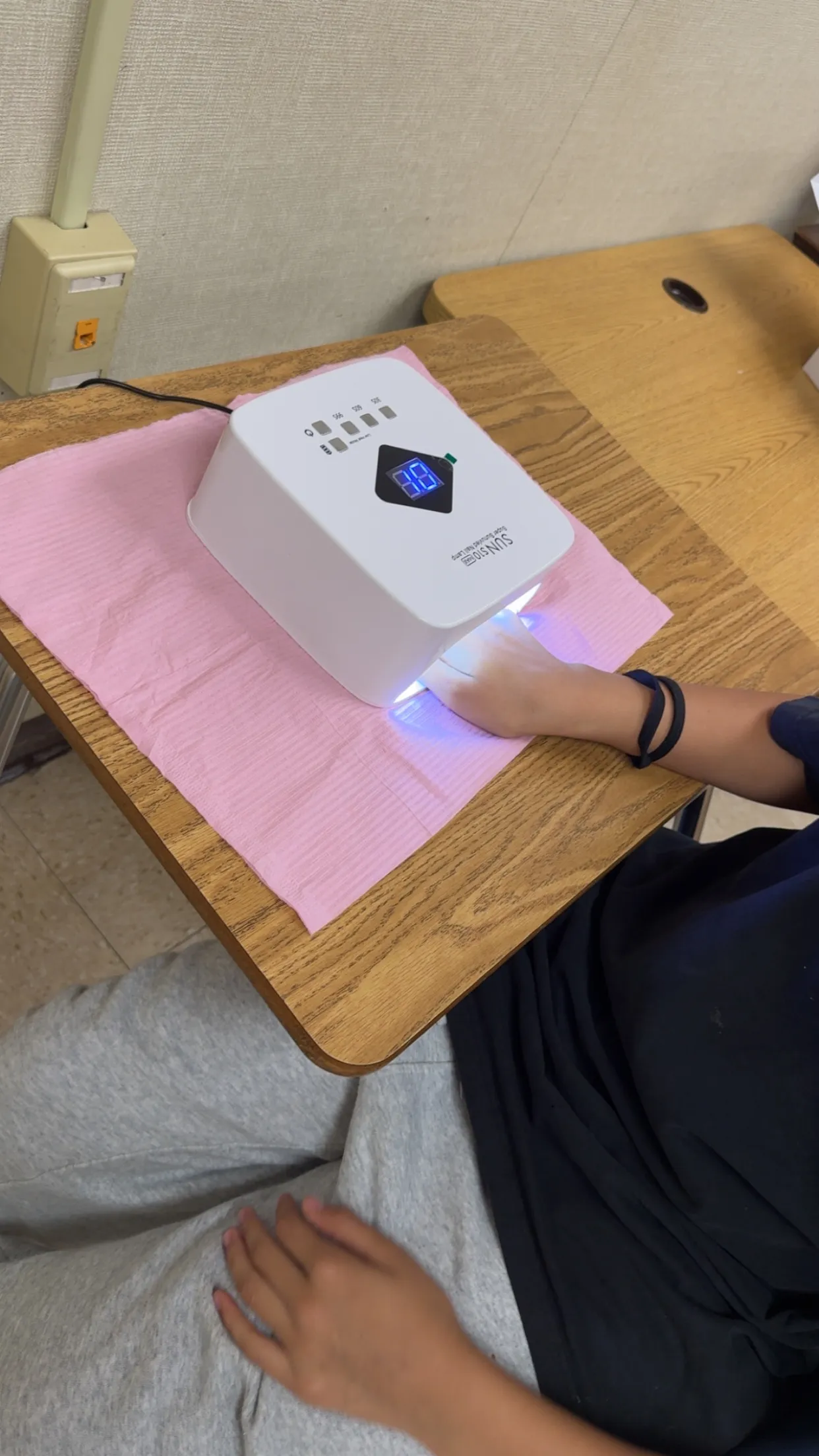 A nail lamp curing a manicure at a workshop table