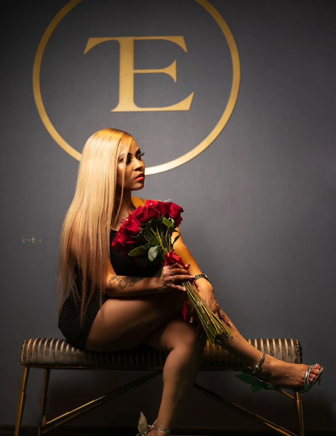 Crystal Michelle, licensed cosmetologist, seated with a bouquet of red roses